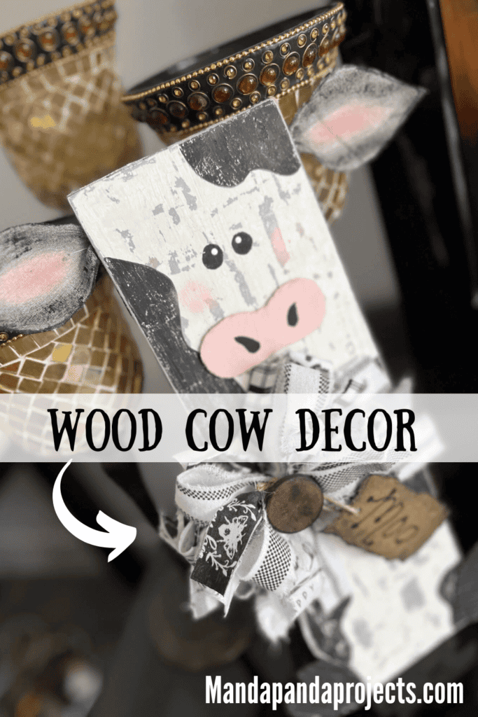 DIY Wood Farmhouse Cow Decor on a chippy cow print rectangular background, fabric ears, big messy black and white fabric bow, and a hangtag that says "Moo".