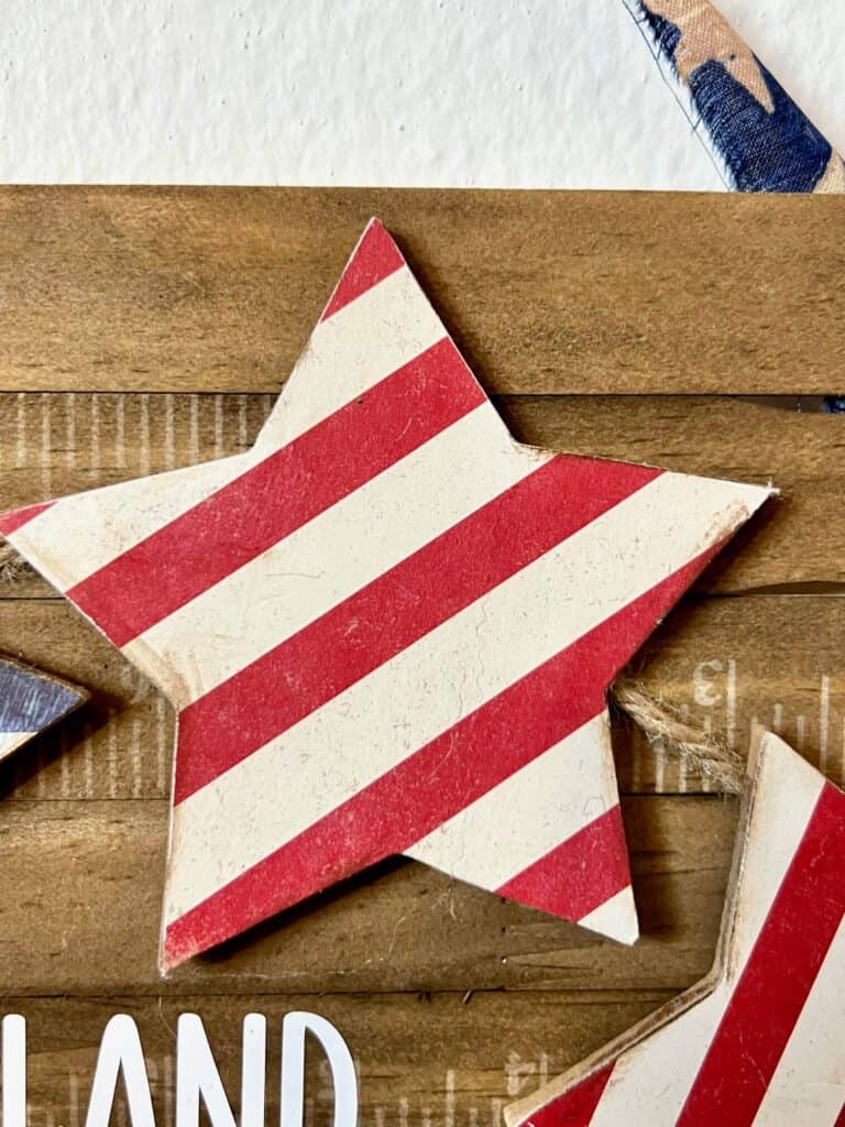 Wood star with red and white striped scrapbook paper decoupaged to it.