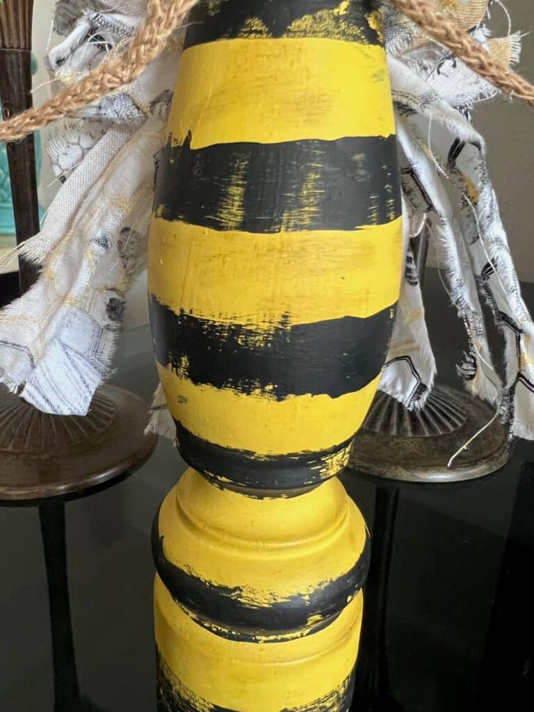 The body of the bee is painted yellow with distressed black stripes.