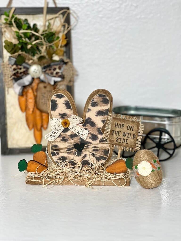 Dollar Tree Leopard Print Bunny Head Decor shelf sitter with 3 mini wood carrots, and a burlap sign that says "Hop on the Wild Side". DIY Decor for Spring and Easter.