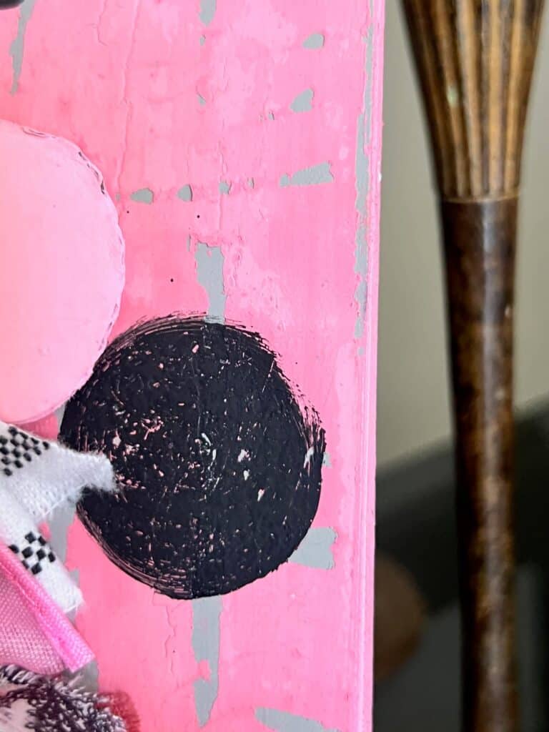 A black polka dot on the pink chippy background.