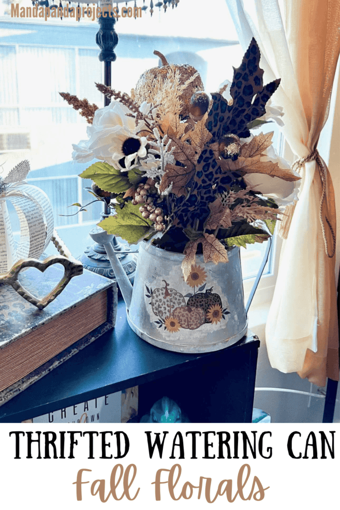 Thrifted watering can flipped into a galvanized metal watering can with a fall floral arrangement, leopard print and gold pumpkin picks, leopard print leaves, and gold acorns, with a leopard print and sunflower pumpkin napkin decoupaged to the front of the watering can for DIY fall centerpiece or home decor.