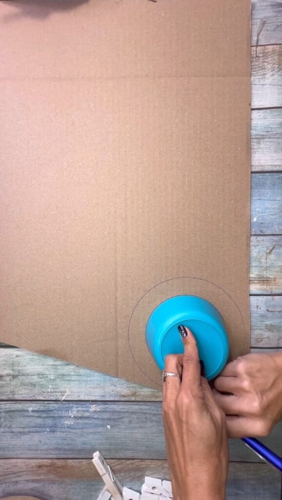 Tracing a small bowl onto a piece of cardboard to make a donut shape.