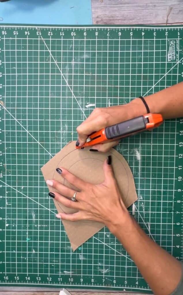 Cutting out the donut shape cardboard with a box cutter.