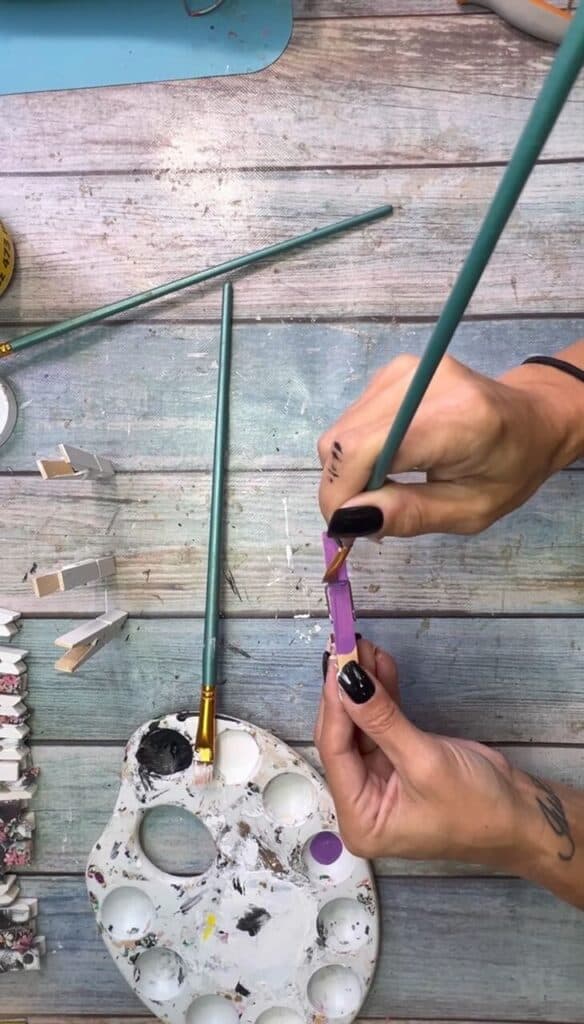 Painting a clothespin purple.