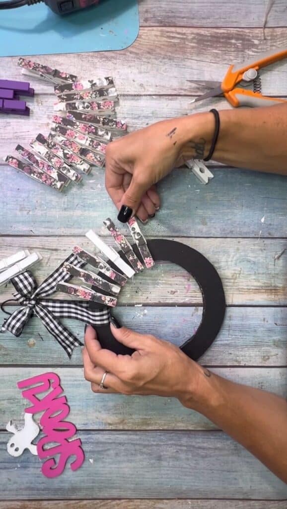 Clipping the clothespins around the cardboard donut to make the shape of the wreath.