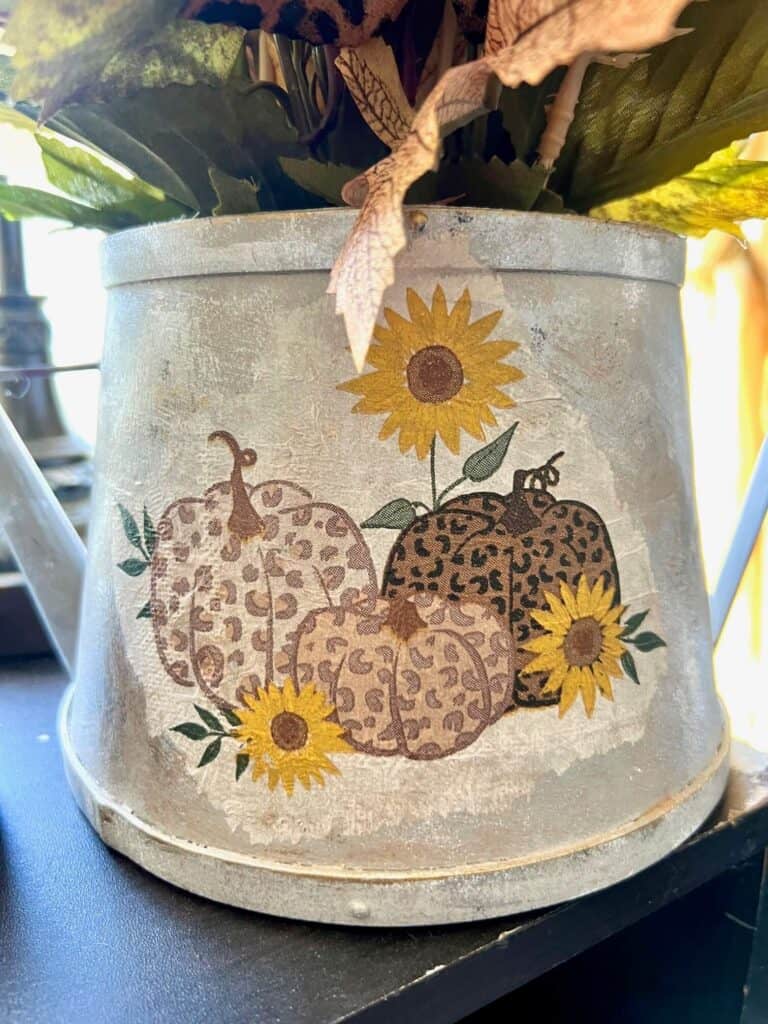 Close up of the leopard print and sunflower pumpkin napkin decoupaged to the front of the galvanized metal watering can.