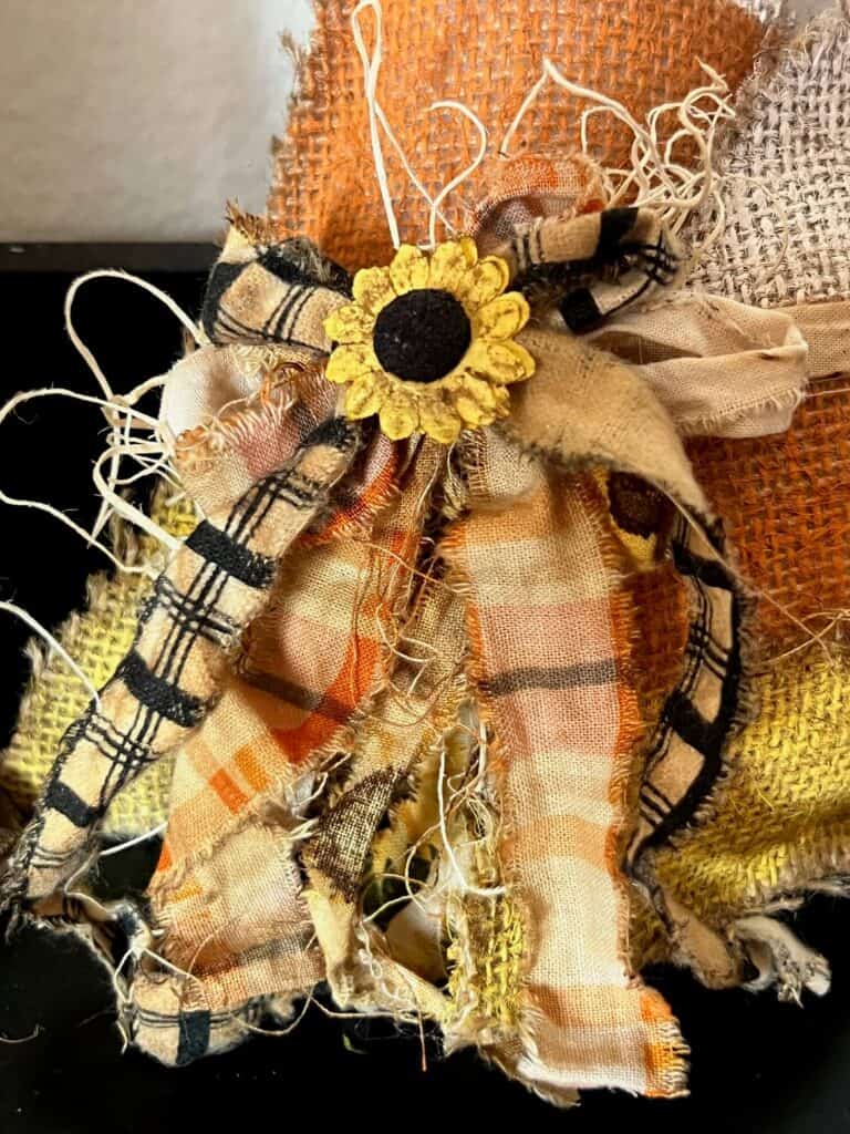 A scrappy coffee stained fabric bow with a sunflower embellishment in the center.