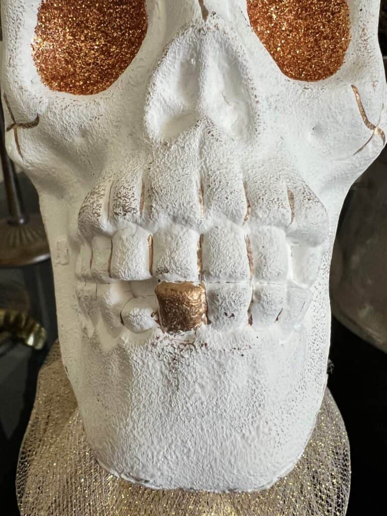 The bottom right tooth of the skull is painted gold.