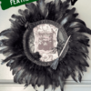 Dollar Tree styrofoam wreath form with black feather trim around the outside, vintage witches rice paper sign in the center, and embellished with faux spiders, mini broomstick, and a black rose for DIY Halloween crafts and decor.