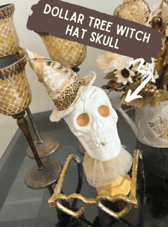 Dollar Tree plastic skull for Halloween, painted white with gold glitter eyes on top of a gold candlestick with a gold tulle neck collar and a witches that was redone with neutral and leopard print fabric and a feather in it