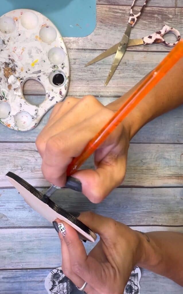 Painting the edges of the wood plaque black.