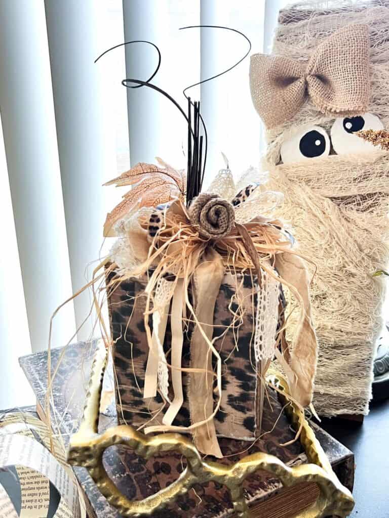 Scrap Wood Block Chunky Neutral Pumpkin with gold, leopard print, hymnal sheet, and a messy bow with a burlap flower and fall leaf embellishment.