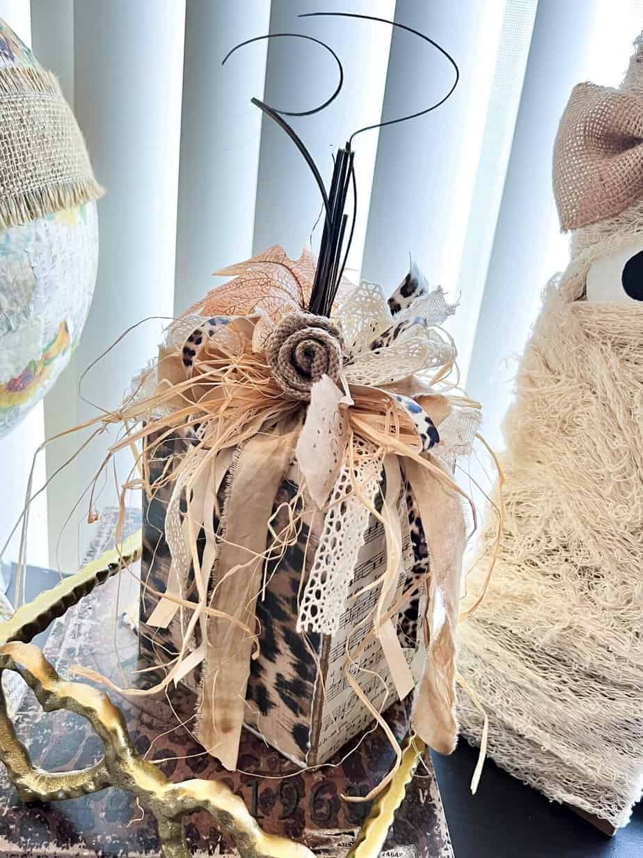 Scrap Wood Block Chunky Neutral Pumpkin with gold, leopard print, hymnal sheet, and a messy bow with a burlap flower and fall leaf embellishment.