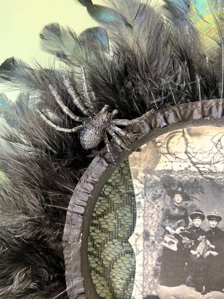 A black sparkly spider glued to the top of the Halloween Feather Wreath.