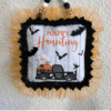 Dollar Tree Halloween Pot Holder with a Ghost, bats, and an old truck that says "Happy Haunting with orange tulle trim around the edge and a black and white buffalo check wood bead hanger, DIY doorknob hanger.