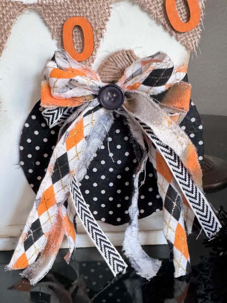 A pumpkin that is black and white polka dots along with an orange and black bow at the top and a wine stem.