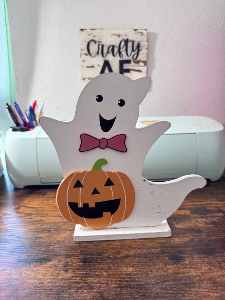 Standing wood ghost from a thrift store with an orange pumpkin.