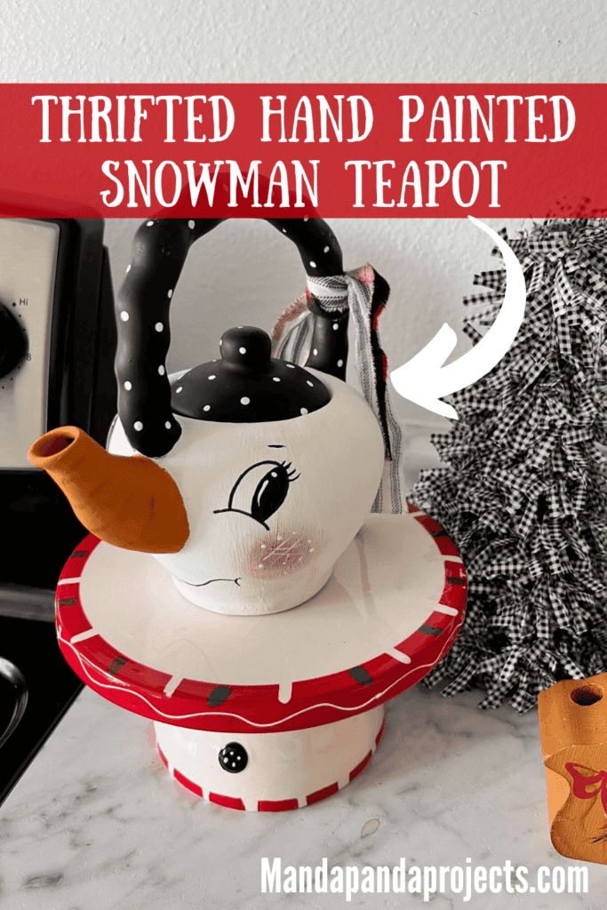 Thrifted Hand painted snowman teapot with the "spout" painted orange as the "carrot" nose, big black eyed, rosy pink cheeks, black and white polka dot handle, and a black, red, and white scrappy fabric bow on the handle.