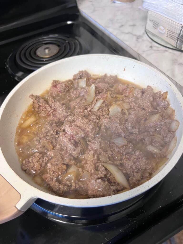 Ground. beef and onion cooking in a pan on the stove.