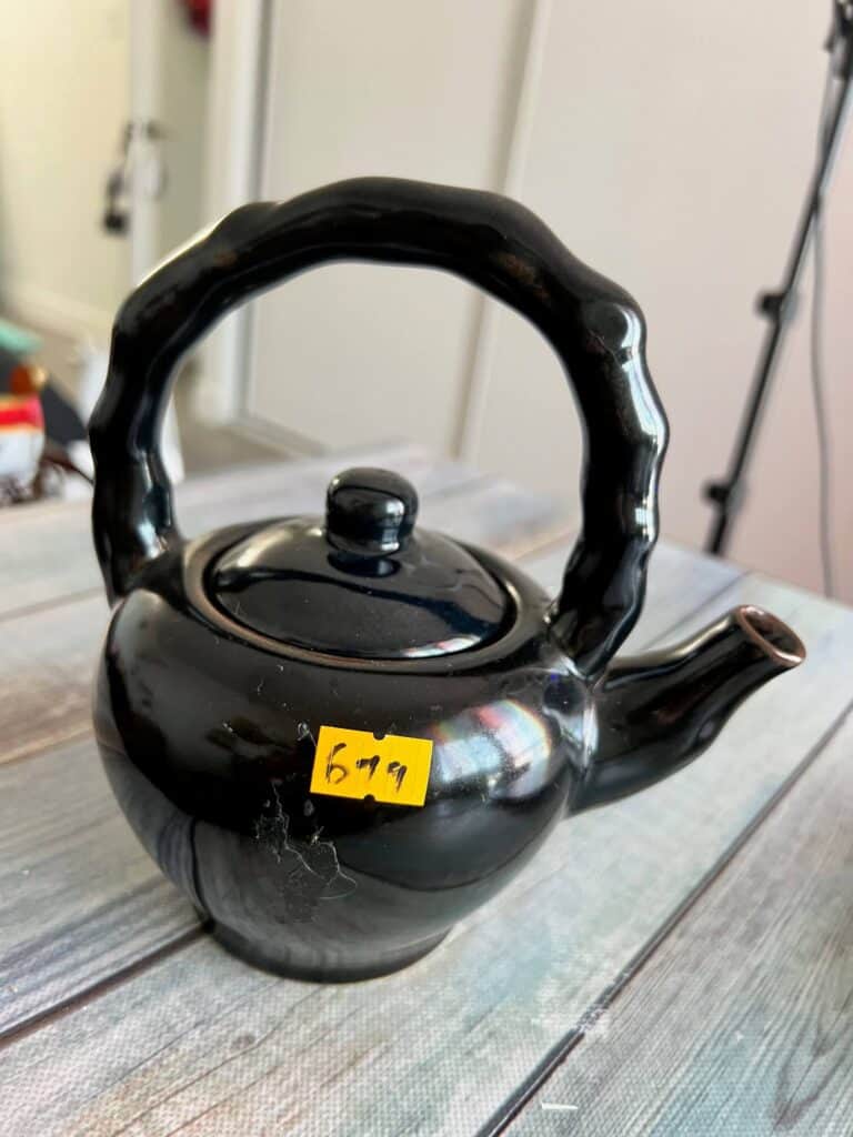 Black thrifted teapot with a price tag that says $6.99.