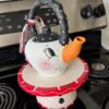 Thrifted Hand painted snowman teapot with the "spout" painted orange as the "carrot" nose, big black eyed, rosy pink cheeks, black and white polka dot handle, and a black, red, and white scrappy fabric bow on the handle.