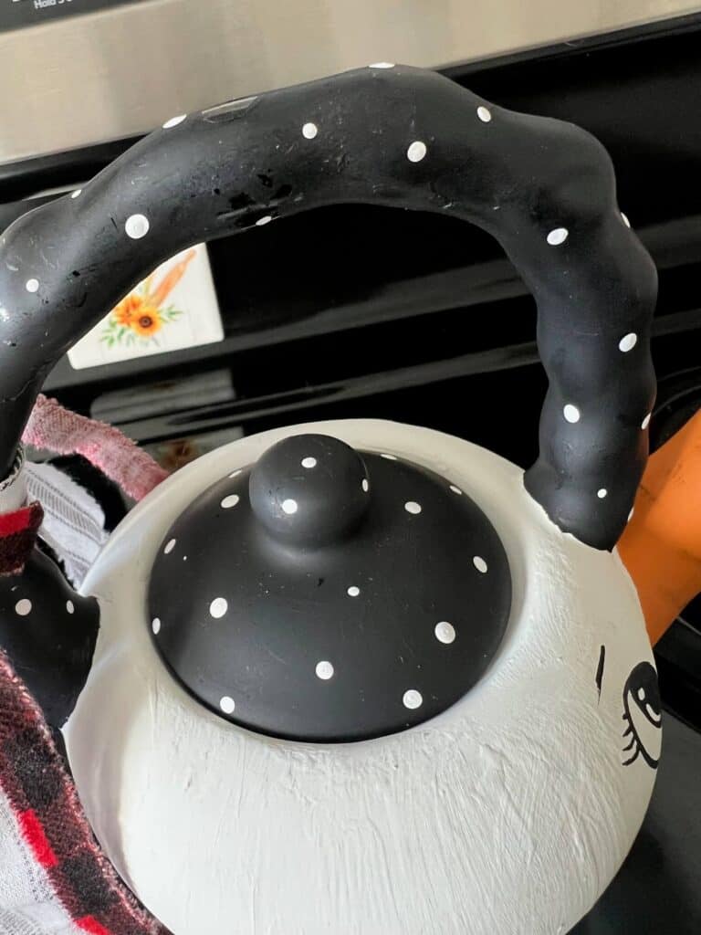 The handle and the top of the teapot painted black with small white polka dots.