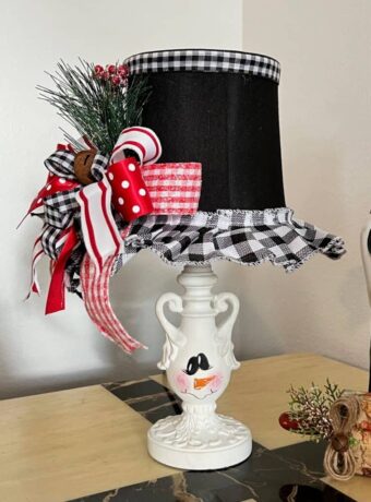 Turn and ordinary thrift store small lamp into adorable and budget friendly Christmas and Winter decor by painting it to look like a snowman. With the lampshade being the "top hat" with a cute red, black, and white bow and a jingle bell, and the lamp body painted like a snowman face.