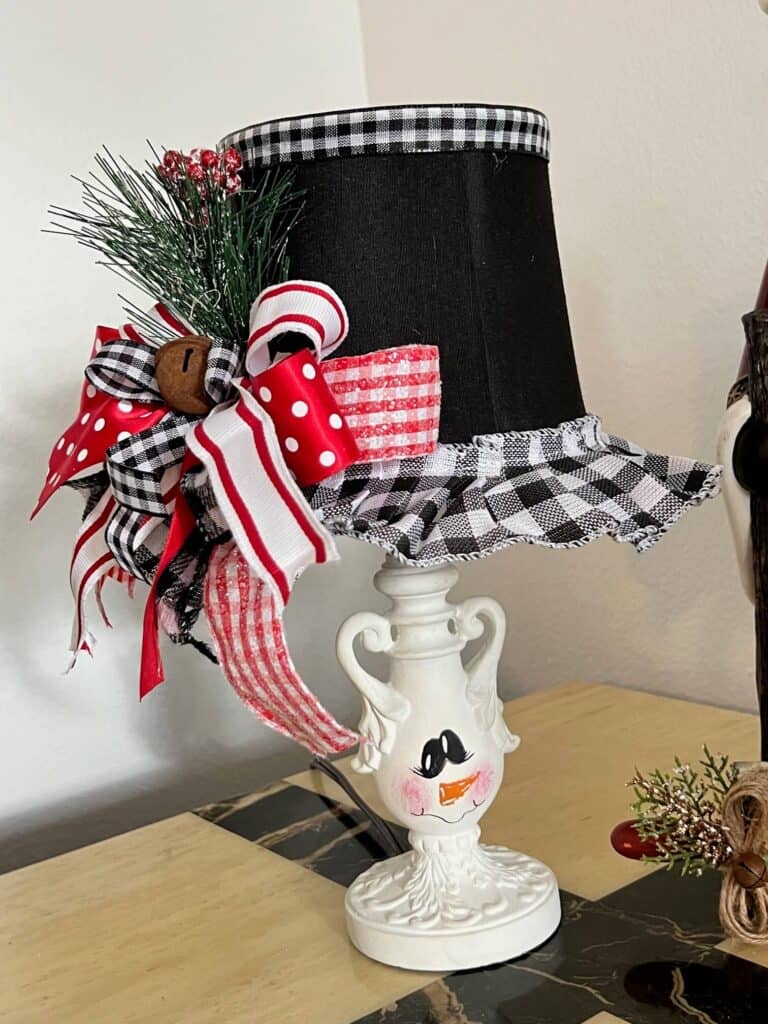 Turn and ordinary thrift store small lamp into adorable and budget friendly Christmas and Winter decor by painting it to look like a snowman. With the lampshade being the "top hat" with a cute red, black, and white bow and a jingle bell, and the lamp body painted like a snowman face. 