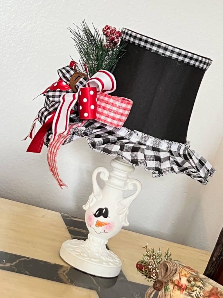 Turn and ordinary thrift store small lamp into adorable and budget friendly Christmas and Winter decor by painting it to look like a snowman. With the lampshade being the "top hat" with a cute red, black, and white bow and a jingle bell, and the lamp body painted like a snowman face. 