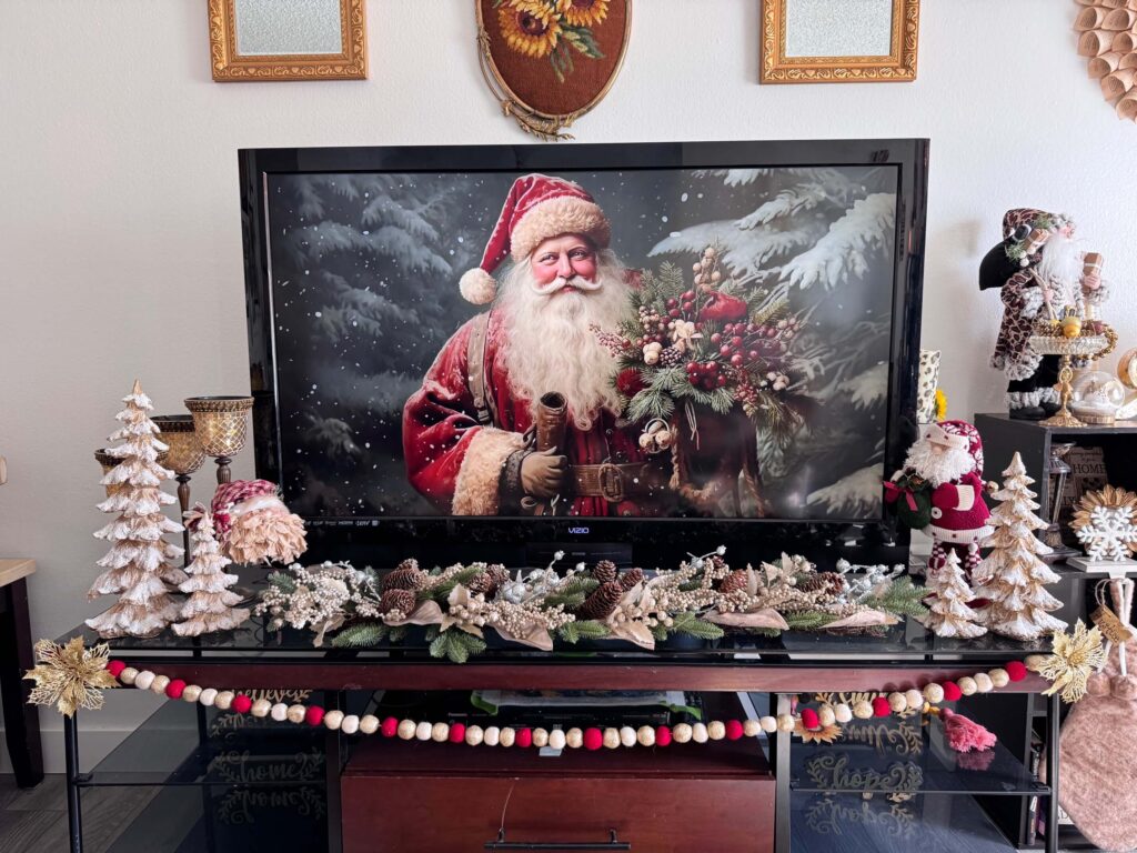 TV stand decorated with christmas with vintage Santa art on the TV.