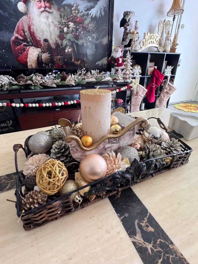 Coffee table centerpiece with pine cones, gold ornament bulbs, and a DIY winter sled with gold candle.