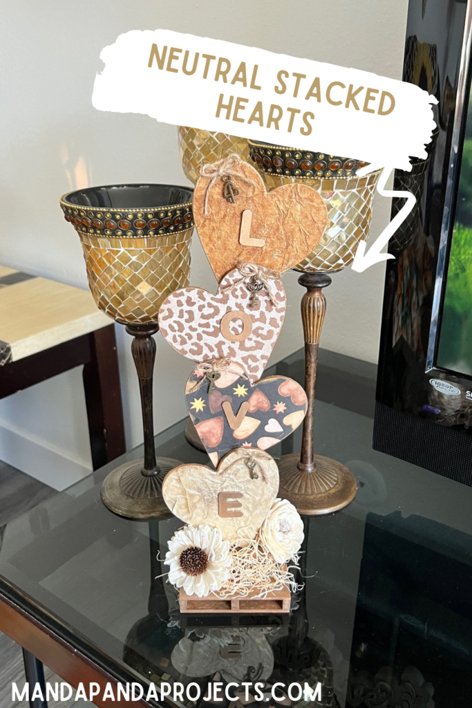 Neutral Stacked Hearts with the word LOVE in gold with leopard print, brown, and creme colors and sola wood flowers at the bottom. The hearts have a twine bow with skeleton key on each of them, perfect for Decor for Valentines Day.