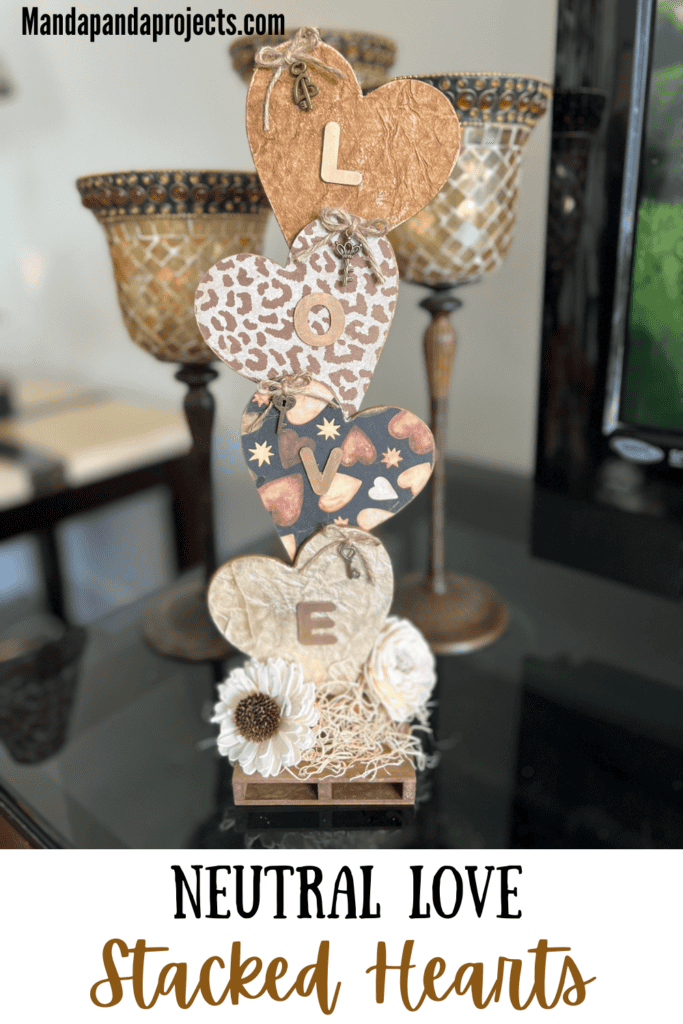 Neutral Stacked Hearts with the word LOVE in gold with leopard print, brown, and creme colors and sola wood flowers at the bottom. The hearts have a twine bow with skeleton key on each of them, perfect for Decor for Valentines Day.