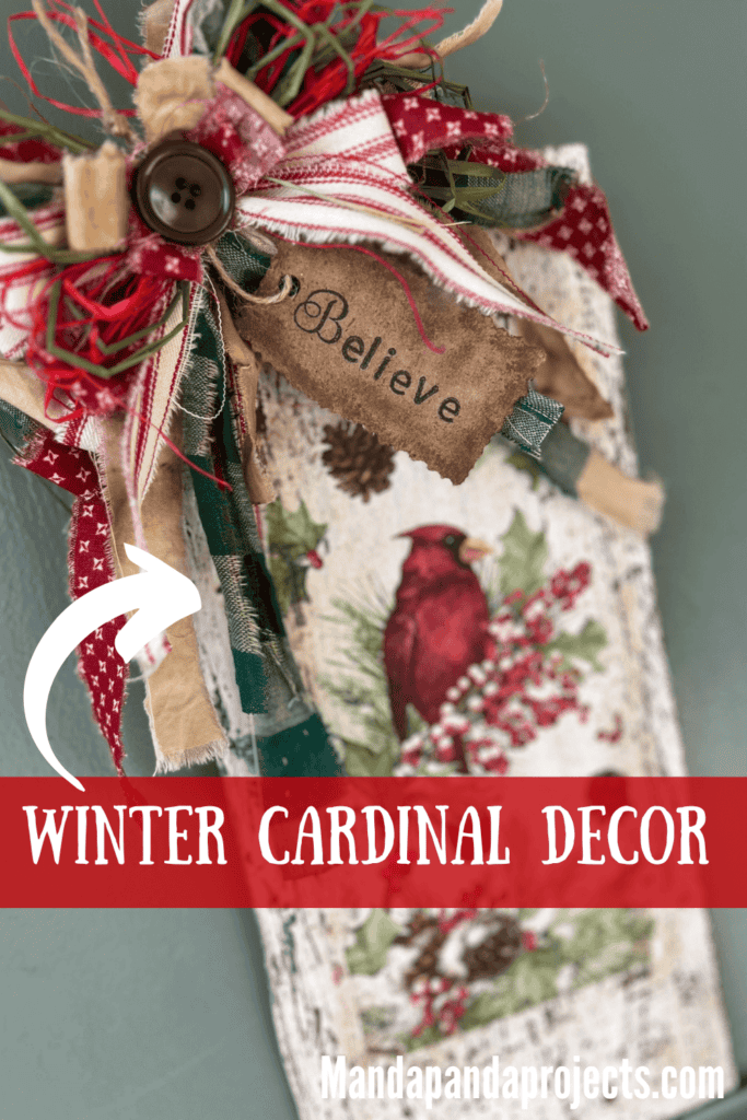 Winter cardinal napkin decoupaged to a distressed white background with a red and green messy bow and a hangtag that says "Believe". Cardinal Napkin Sign