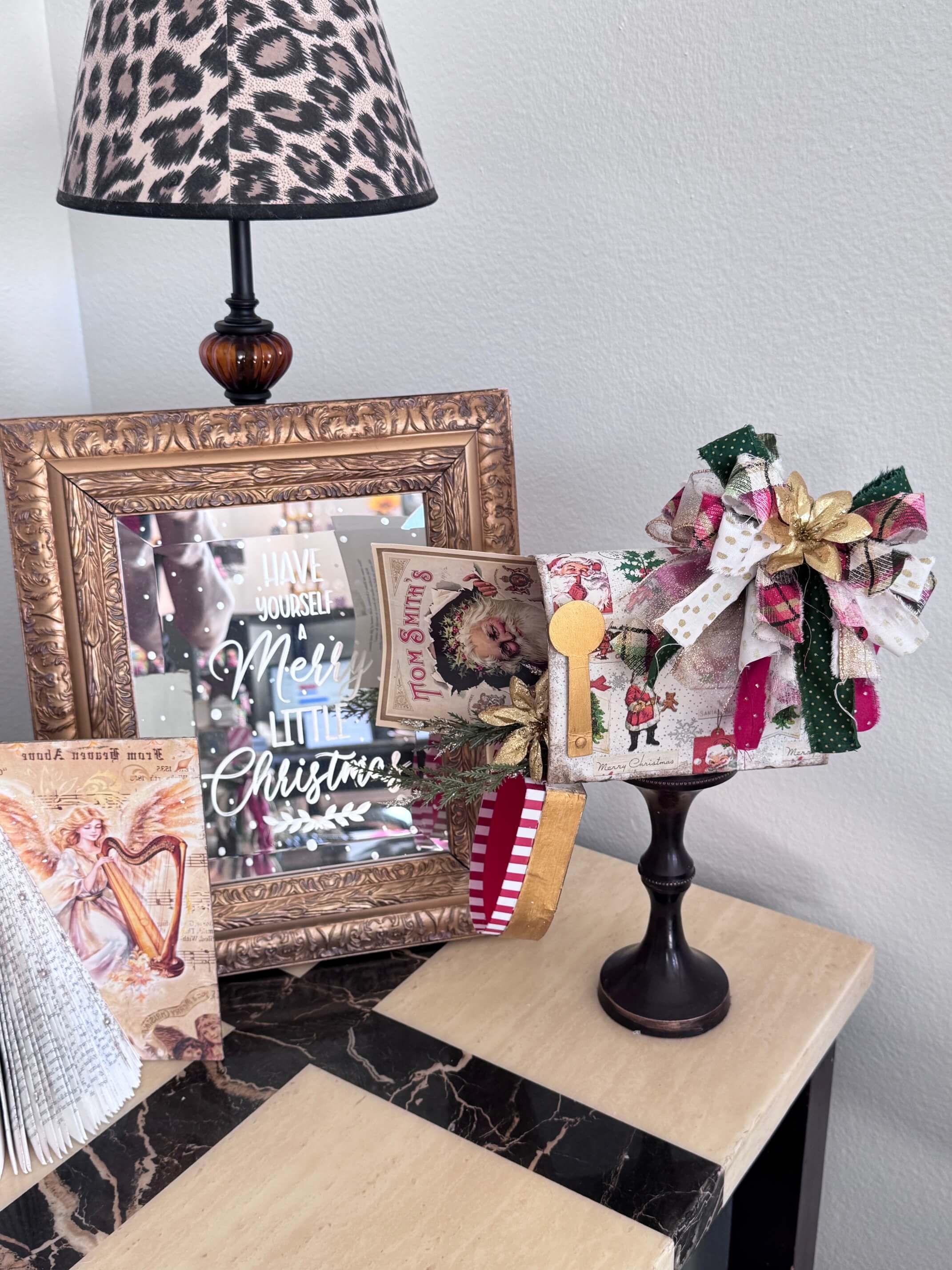 The completed Dollar Tree Christmas Mailbox next to some other christmas decor on an end table.