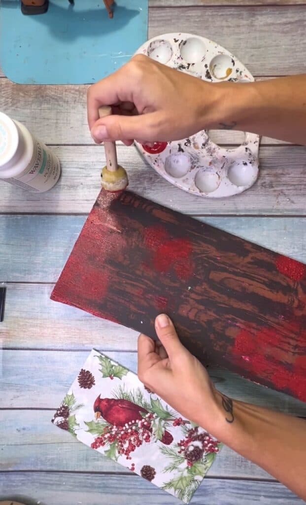 Brown wood surface with a spouncer randomly dabbing red throughout the surface