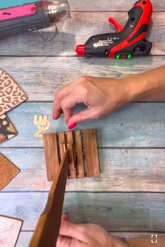 Gluing the paint stick into the wood pallet base with hot glue and reinforced by Jenga blocks.