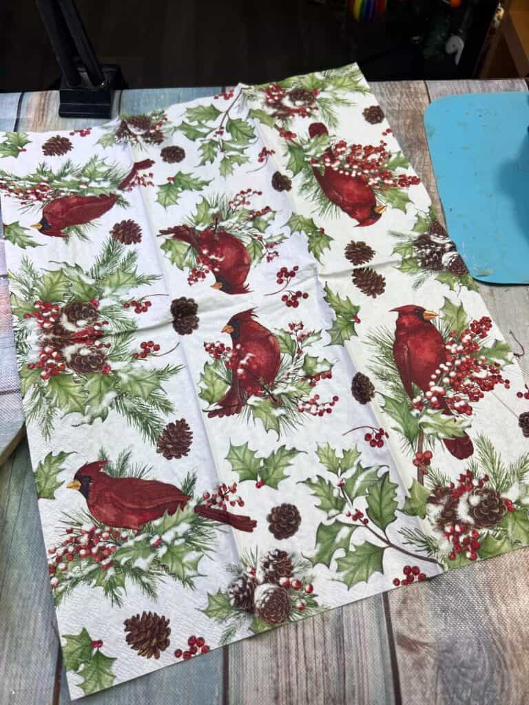 Cardinal napkin with greenery and pine cones.