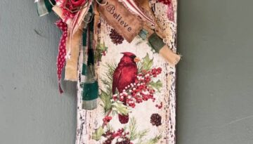 Winter cardinal napkin decoupaged to a distressed white background with a red and green messy bow and a hangtag that says "Believe". Cardinal Napkin Sign