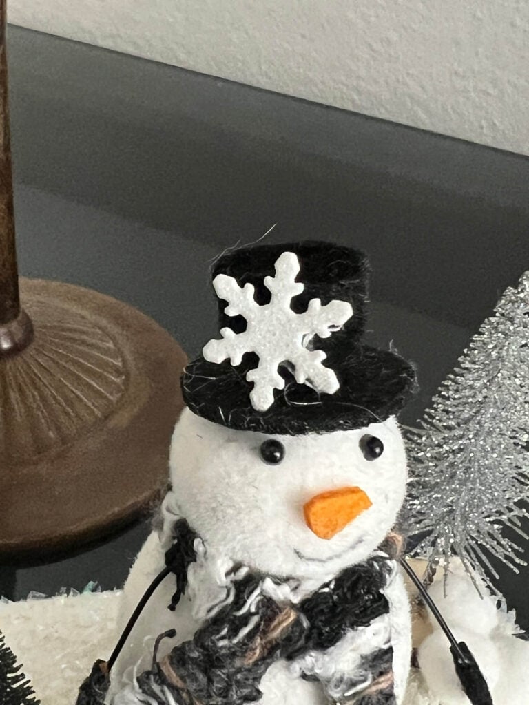 A snowflake embellishment glued to the snowmans top hat.