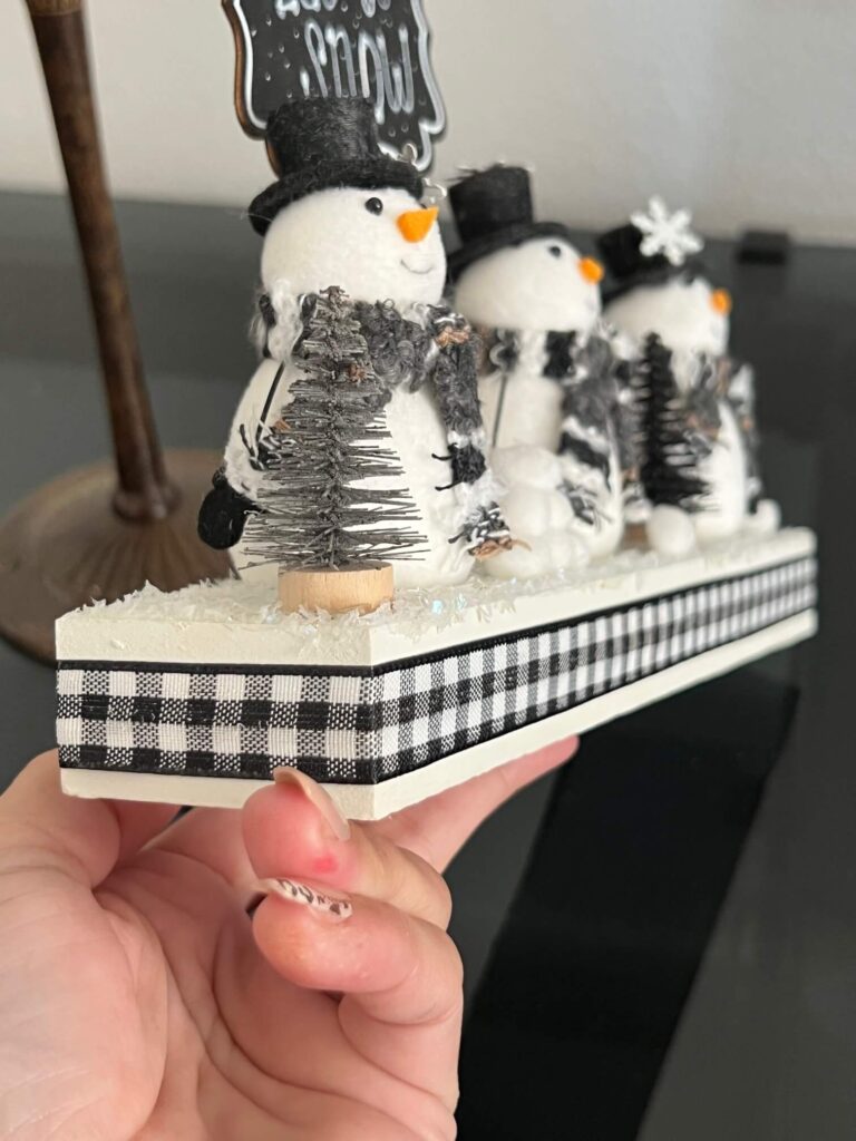 Glue black and white buffalo check ribbon around the base of the snowman shelf sitter.