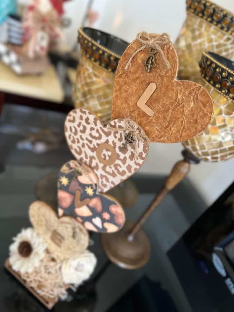 Neutral Stacked Hearts with the word LOVE in gold with leopard print, brown, and creme colors and sola wood flowers at the bottom. The hearts have a twine bow with skeleton key on each of them, perfect for Decor for Valentines Day.