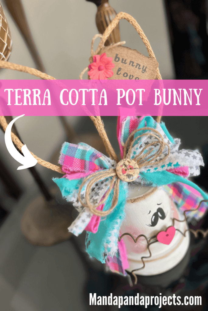 White Terra Cotta Pot Bunny with wired jute ears, a pink, purple, and teal messy fabric bow and a cute tag on her ear that says "bunny love" for spring and easter crafts and decor. 