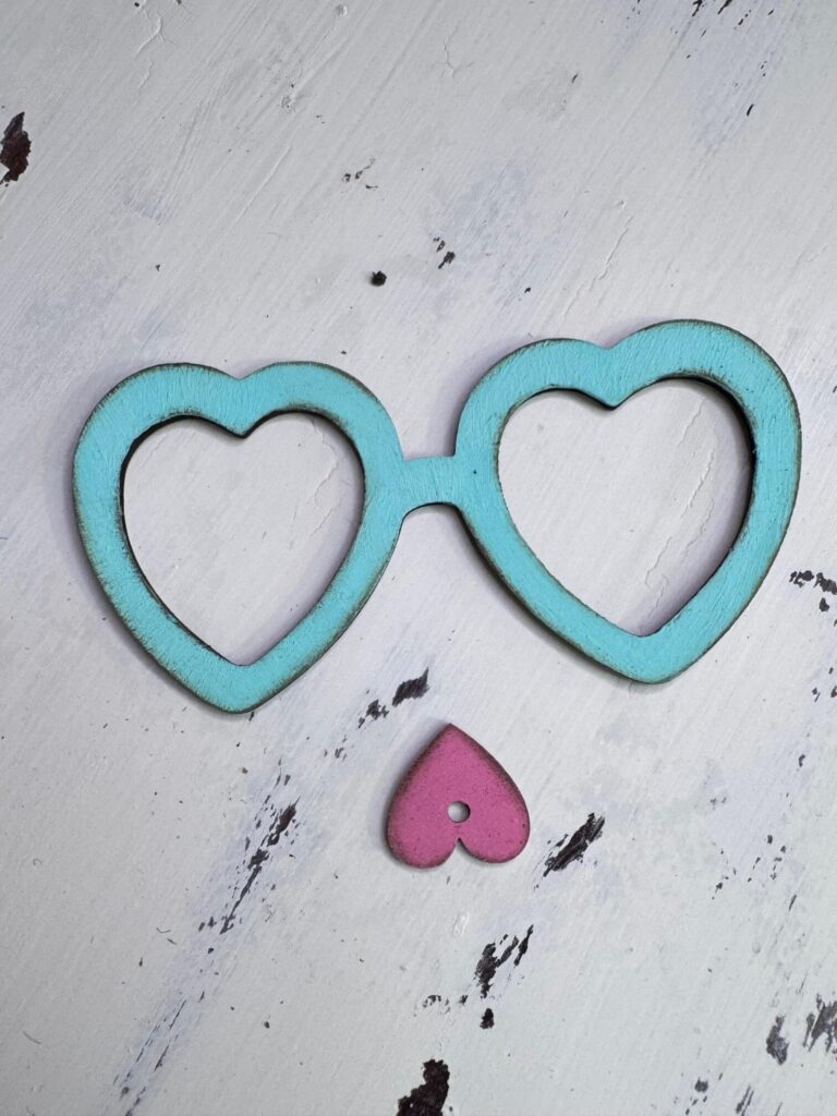 Heart shaped eyeglasses painted Teal and a pink heart nose.