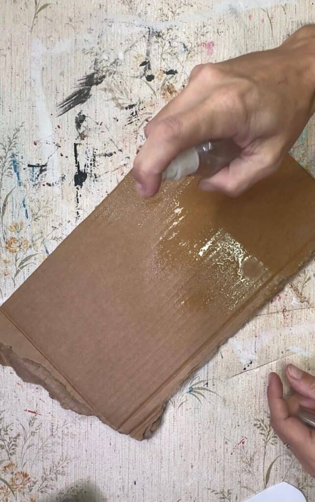 Spraying the cardboard with water.