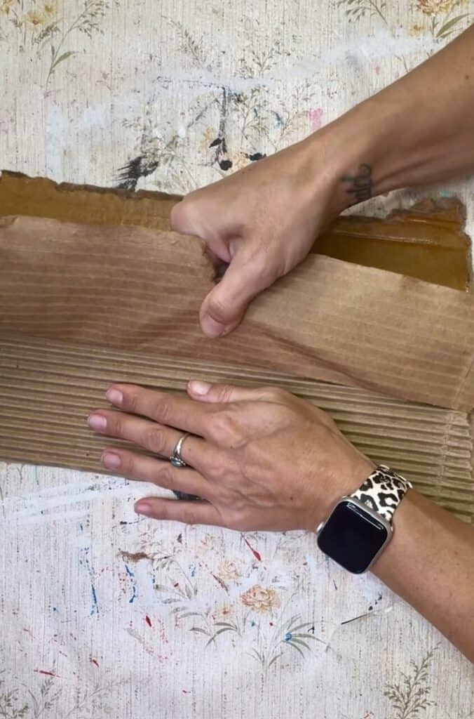 Peeling the top layer of cardboard pff to expose the corrugated part.