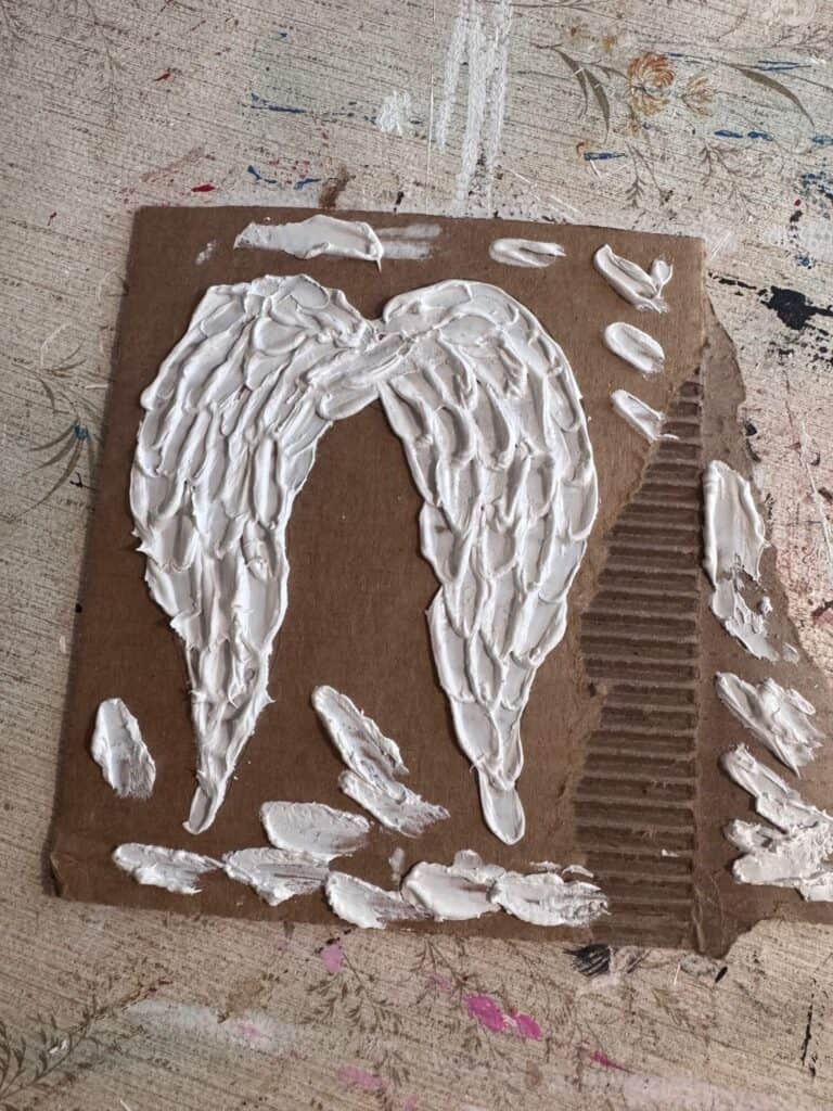 Practicing with the joint compound angel wings on cardboard.