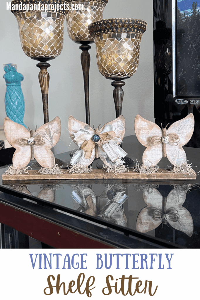 3 Wood Butterfly shelf sitter with a vintage vibe with a spring hangtag and twine and fabric bows, sitting on a base with spanish moss.