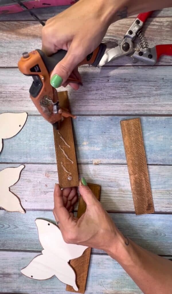 Add hot glue to one of the wood shims to glue them together.